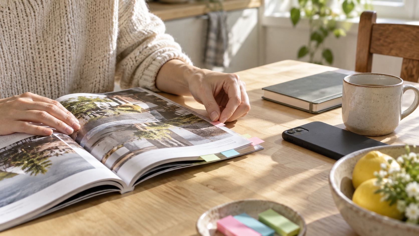 Reader marking favorite magazine pages with colored tabs beside a face-down phone and notebook.