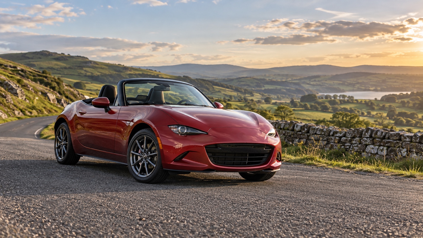 A compact red two-seat roadster at a turnout beside a winding country road.