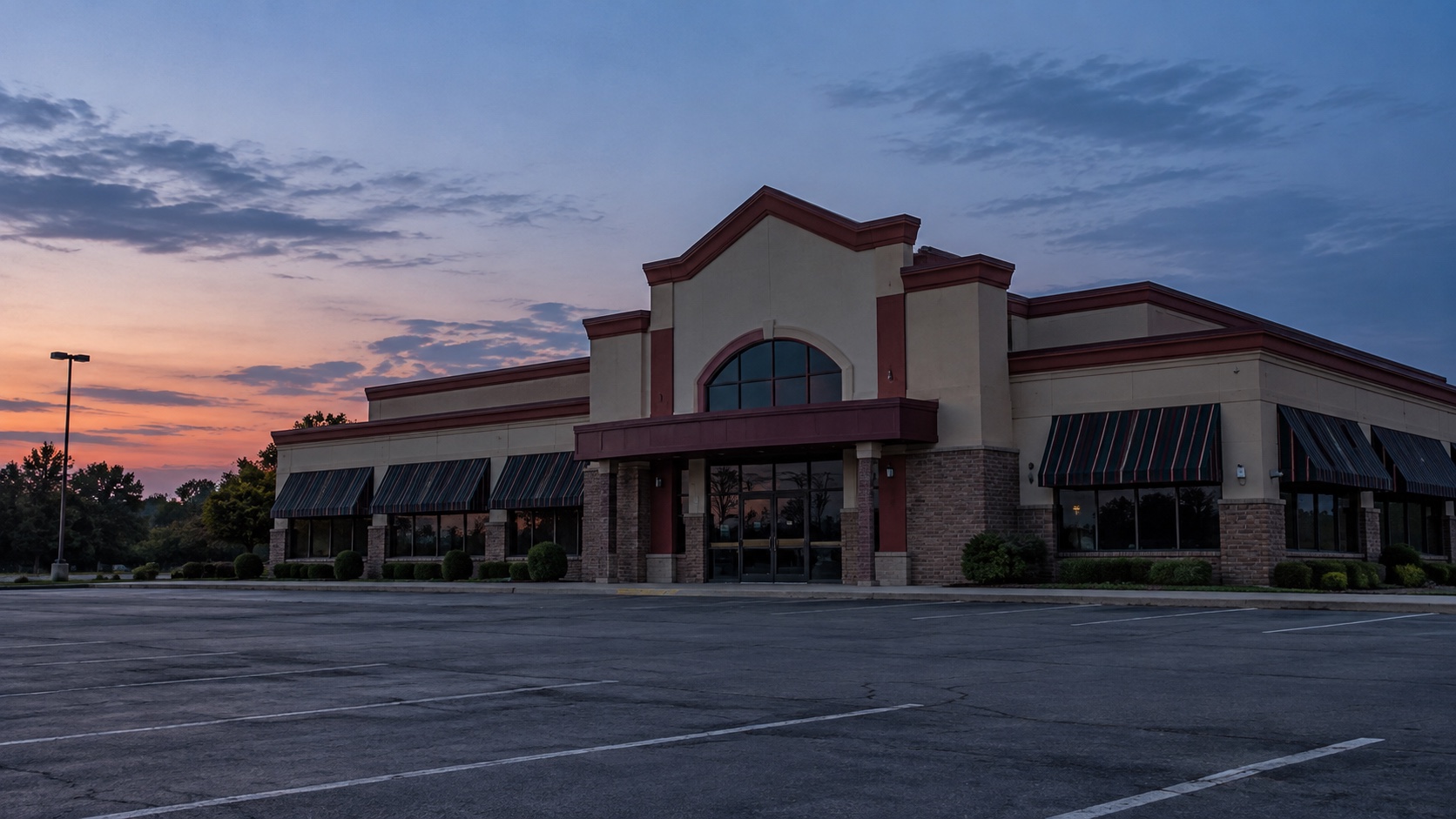 Unbranded intact suburban family steakhouse exterior with an empty parking lot at dusk.